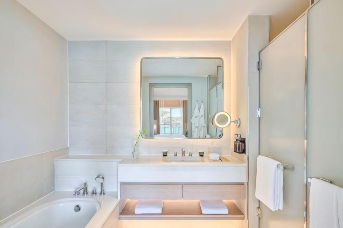 A modern bathroom with a bathtub, a sink with a mirror, and a shower area.