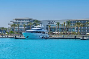 A large yacht docked at a marina with a modern building labeled "VIDA MARINA MARASSI" in the background. - Vida Marina Resort Marassi (El Alamein)