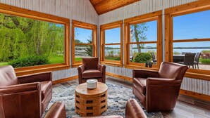 Une pièce dotée de grandes fenêtres, d’un plafond en bois et de fauteuils en cuir.