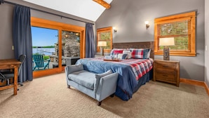 Une chambre avec un grand lit, un bureau, une chaise et une vue sur l’extérieur.