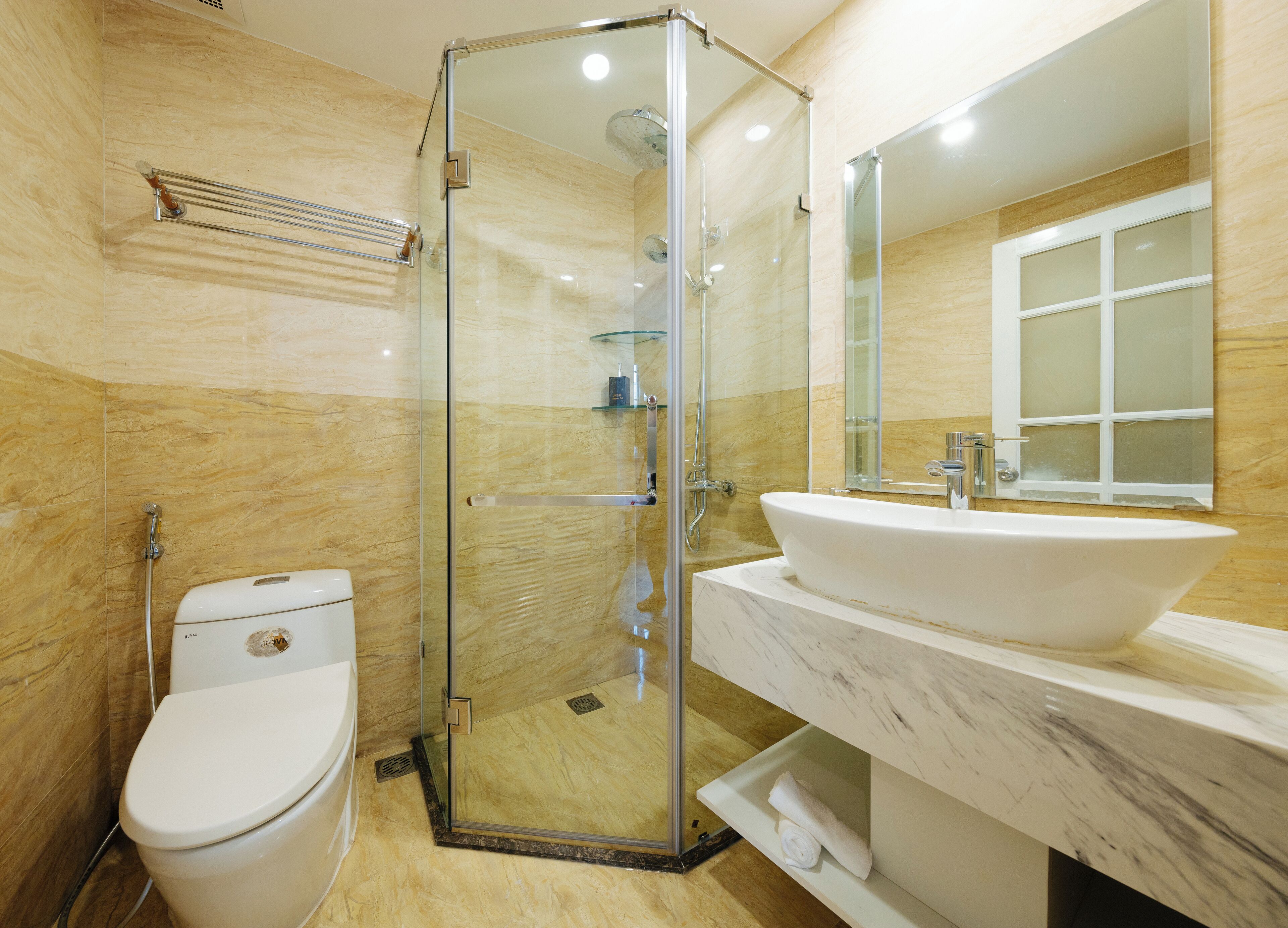 Un baño moderno con ducha de vidrio, un lavamanos blanco y un inodoro.