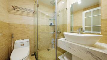Un baño moderno con ducha de vidrio, un lavamanos blanco y un inodoro.