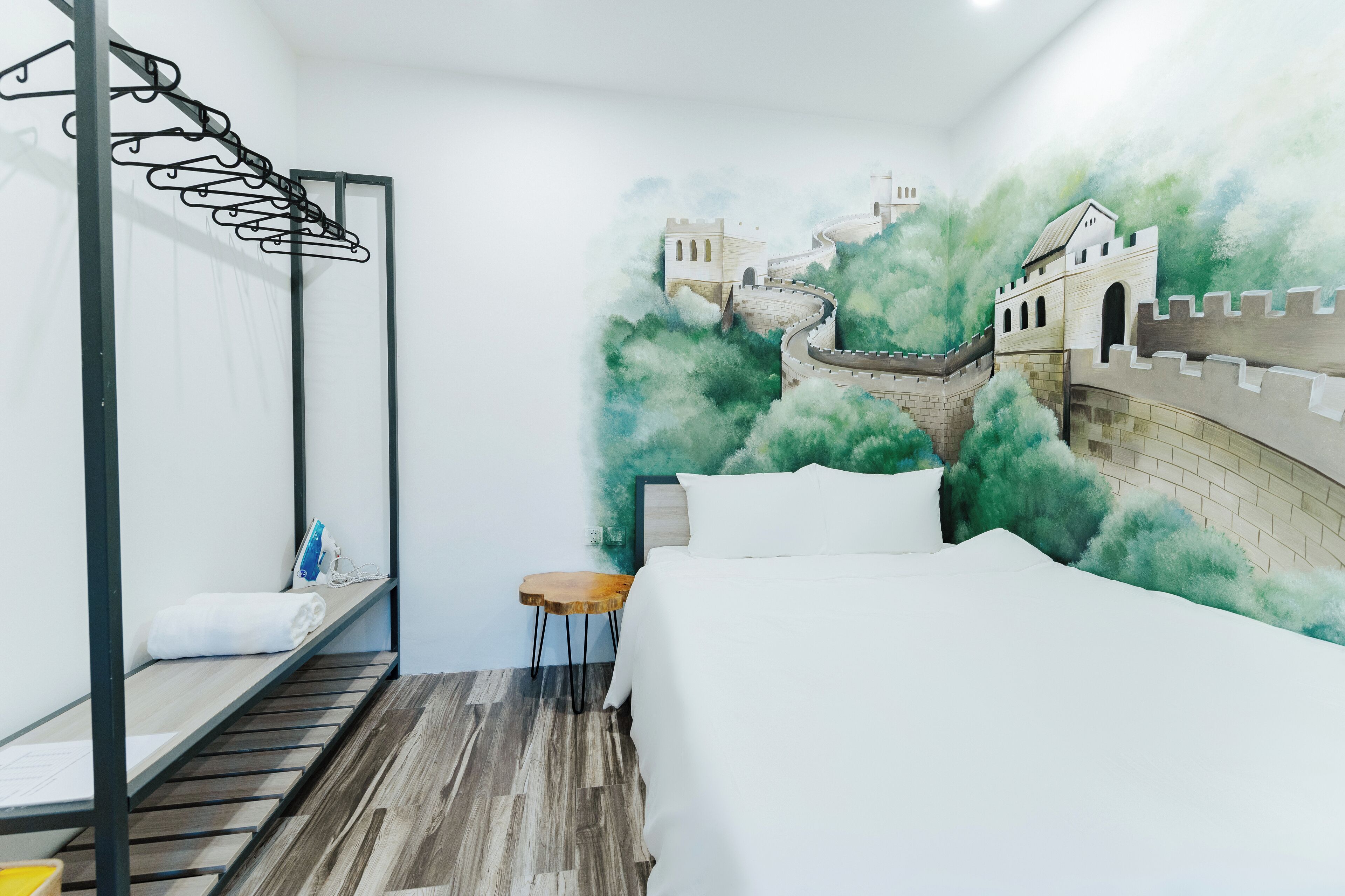 A hotel room with a bunk bed, a small wooden table, and a mural of a castle on the wall.