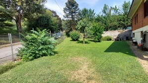 A well-maintained garden with a lawn, a stone wall, and a brick building with a window and a door. - A LITTLE NEST (Ivrea)