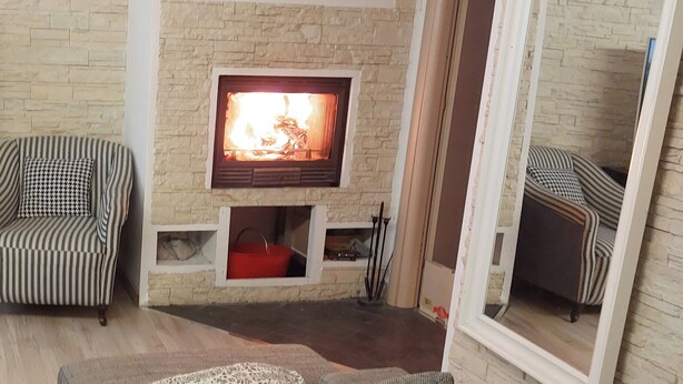 A cozy living room with a fireplace, striped sofas, and a stone wall. - A LITTLE NEST (Ivrea)