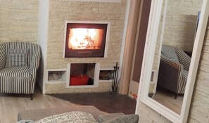 A cozy living room with a fireplace, striped sofas, and a stone wall. - A LITTLE NEST (Ivrea)