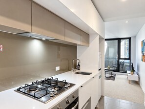 Una cucina moderna con piano cottura a gas, lavello e finestra vista su un'area pranzo.
