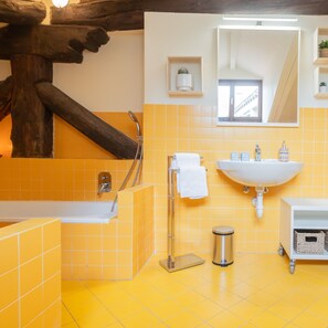 A bathroom with yellow tiles, a white sink, a bathtub, and a wooden beam structure. - Plinio 10 in Como With 2 Bedrooms and 2 Bathrooms (Como)