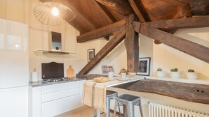 A kitchen with white cabinets, a wooden ceiling, and a radiator. - Plinio 10 in Como With 2 Bedrooms and 2 Bathrooms (Como)