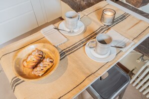 A breakfast setup with pastries, two cups, and a candle on a table. - Plinio 10 in Como With 2 Bedrooms and 2 Bathrooms (Como)
