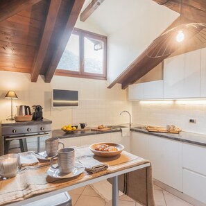 A modern kitchen with wooden beams, a large window, and white cabinets. - Plinio 10 in Como With 2 Bedrooms and 2 Bathrooms (Como)