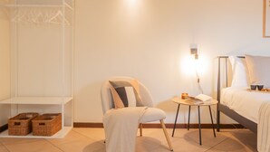 A bedroom with a bed, a chair, a small table, a wardrobe, and a shelf with baskets. - Plinio 10 in Como With 2 Bedrooms and 2 Bathrooms (Como)