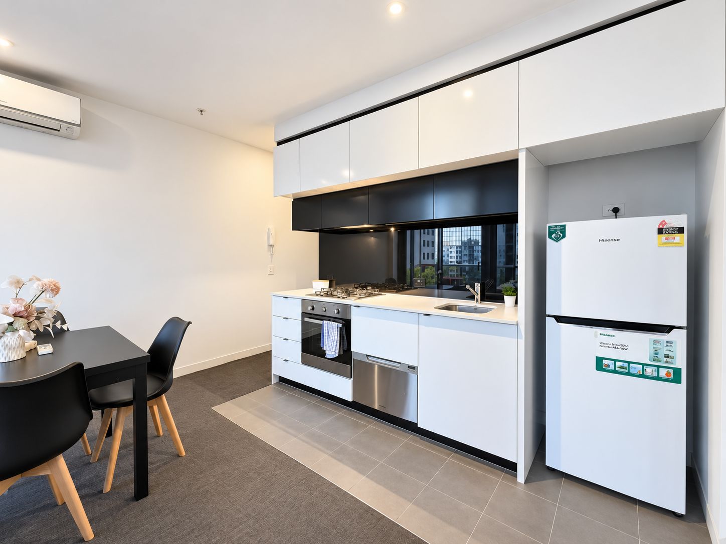A modern kitchen with white cabinetry, a stainless steel sink, and a Hisense refrigerator.