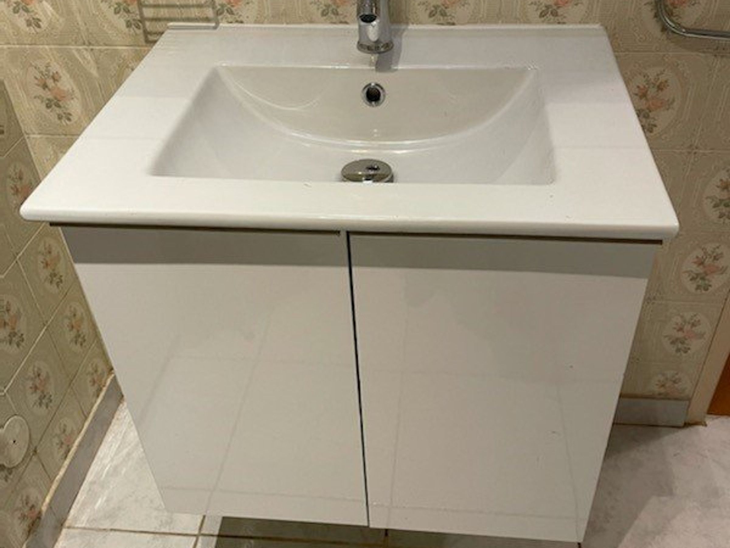 A bathroom with a white sink, a mirror, and a door.