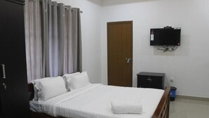 A bedroom with a bed, a wardrobe, a television, and a door. - Zavon Holiday Home -Deluxe Room (Vythiri)
