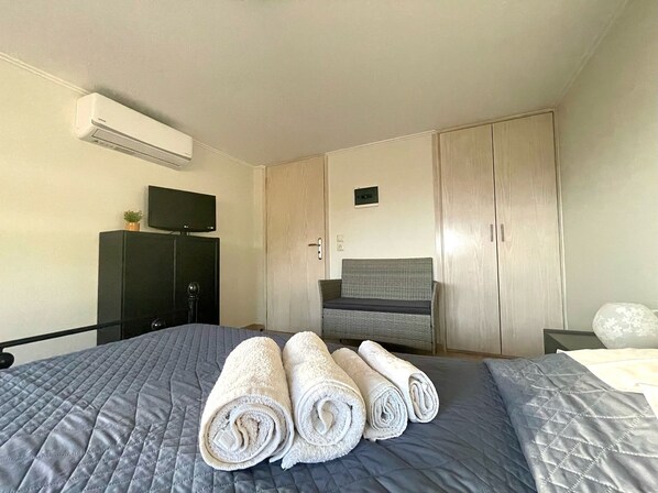 A hotel room with a bed, a TV, a wardrobe, and a chair.