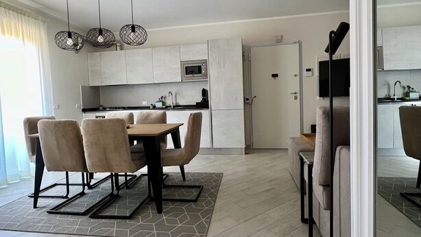 A modern kitchen with a dining area, featuring a dining table with chairs, a kitchen island, and pendant lighting. - Novimo Comfort Apartment with elevator and secure private parking (Terrasini)