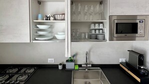 A modern kitchen with a built-in microwave, stainless steel appliances, and a central island with a sink. - Novimo Comfort Apartment with elevator and secure private parking (Terrasini)