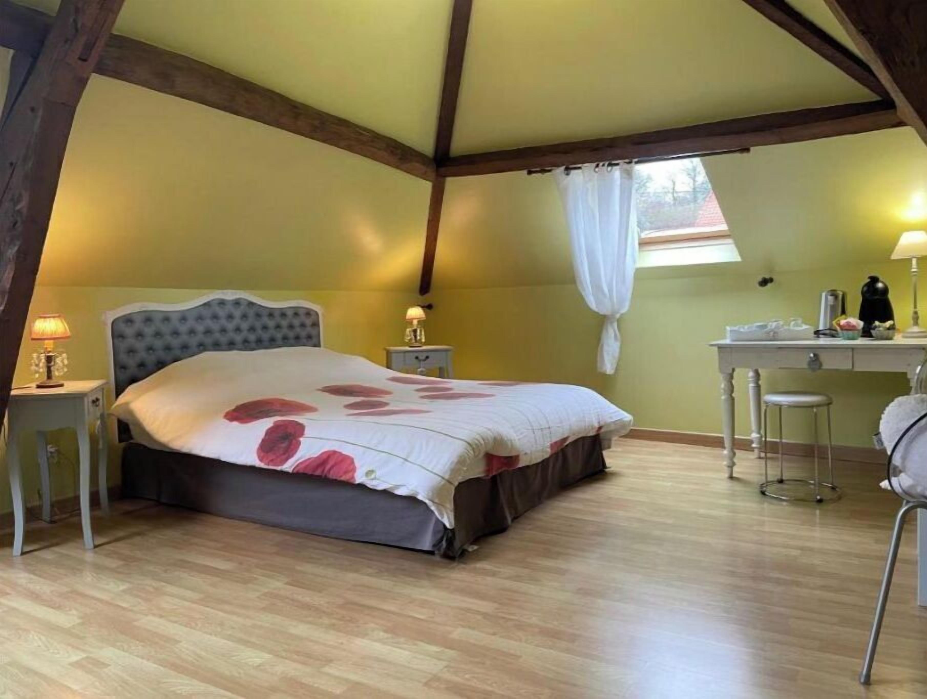 A bedroom with a bed, bedside tables, a desk, and a chair.