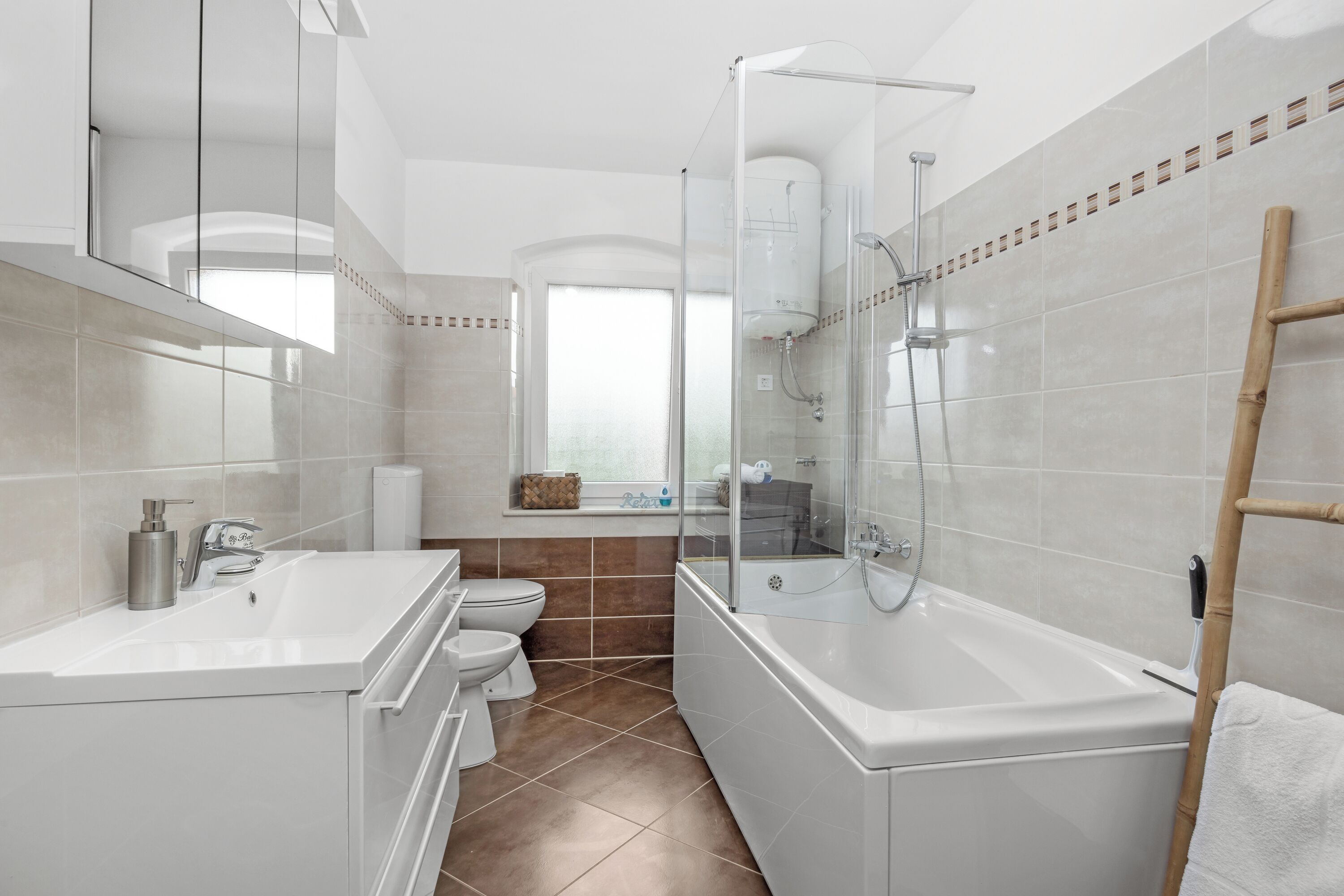 Un baño moderno con ducha envuelta en vidrio, un lavamanos blanco y una bañera.