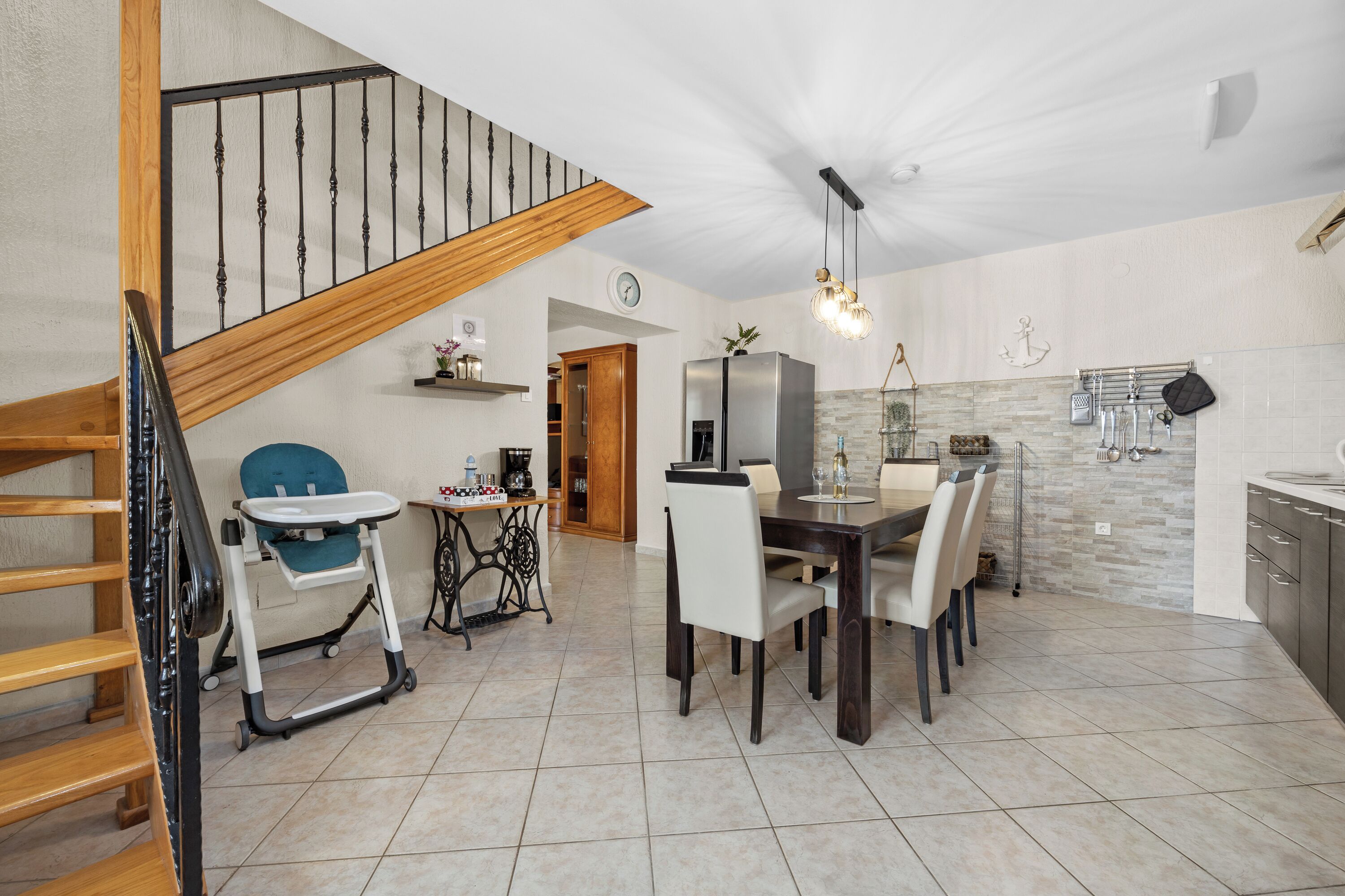 Una cocina amplia con comedor, una escalera de madera y un cambiador para bebés.