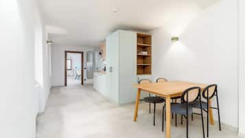 A modern kitchen with white cabinets, a wooden dining table, and black chairs.