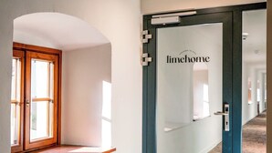 Un couloir avec une porte en verre dépoli portant l’inscription « limehome » et une fenêtre avec un cadre en bois.