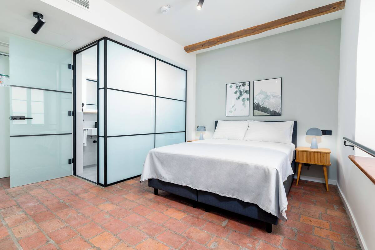 Een slaapkamer met een bed, een kledingkast, een nachtkastje en een wandlamp.