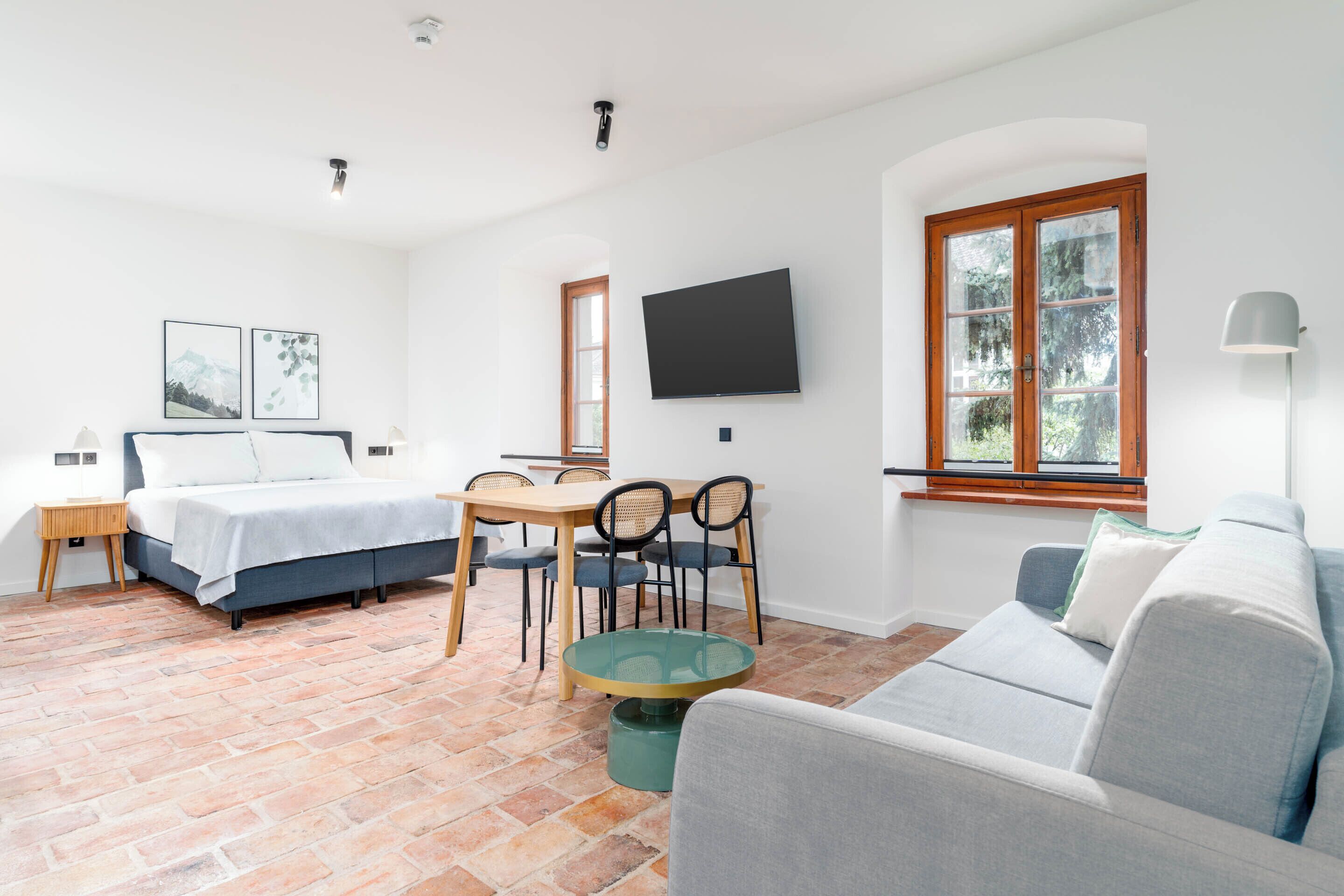 A modern room with a bed, a dining table, and a sofa.