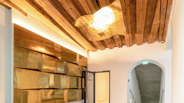 Un hall d’entrée avec un plafond en bois, un grand mur de verre et un sol en briques.