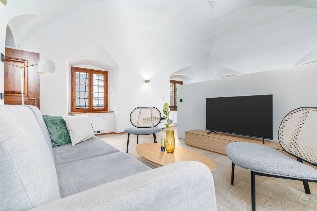 Een moderne woonkamer met een bank, een salontafel, een televisie en een fauteuil.