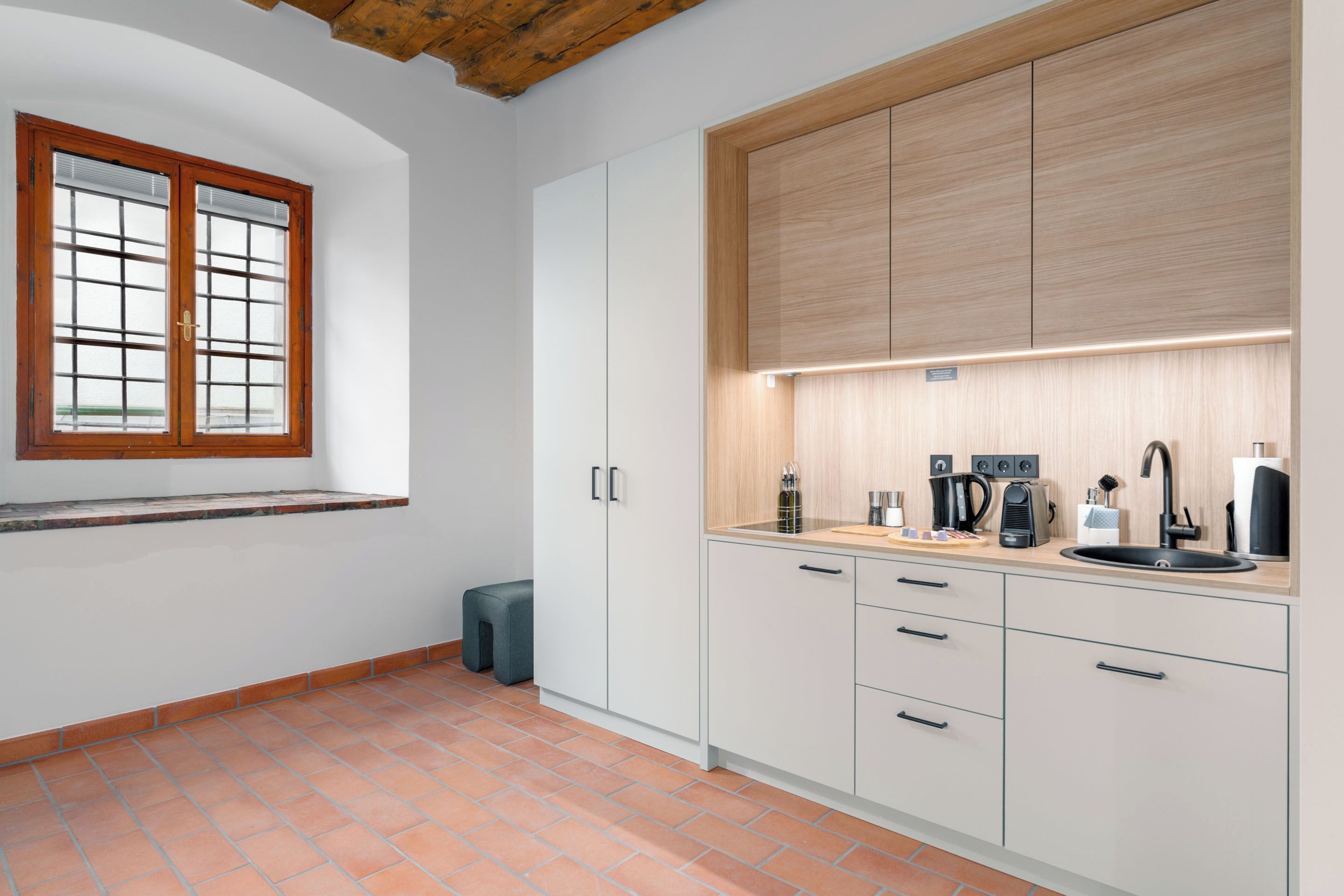 A modern kitchen with white cabinets, a wooden countertop, a built-in oven, and a window with a view.