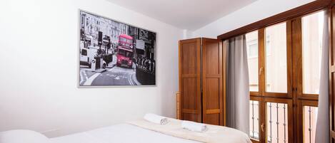 A bedroom with a bed, a wardrobe, and a large window with curtains.