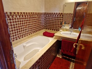 Une salle de bain avec une baignoire, un lavabo et un miroir.