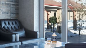 Una habitación moderna con un sofá de cuero, una mesa de vidrio y una botella de Jack Daniel's whiskey.