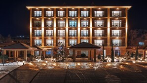 Un hotel de varios pisos con una fachada simétrica, múltiples balcones y un área de entrada cubierta.