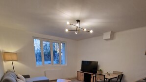 A modern living room with a sofa, a coffee table, a TV, and a dining area.