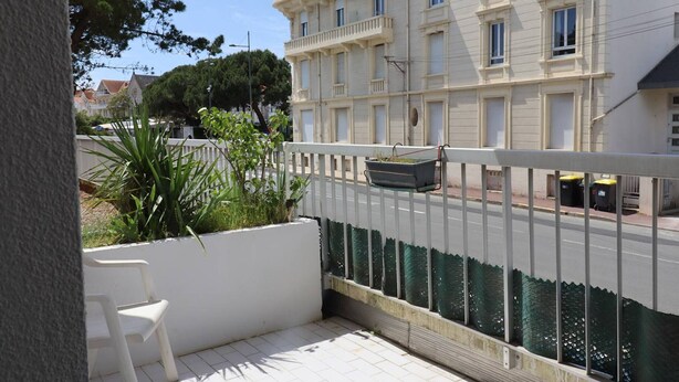 A balcony with a white railing, a small planter, and a white chair. - Cozy apartment in Pontaillac - 4 guests (Royan)