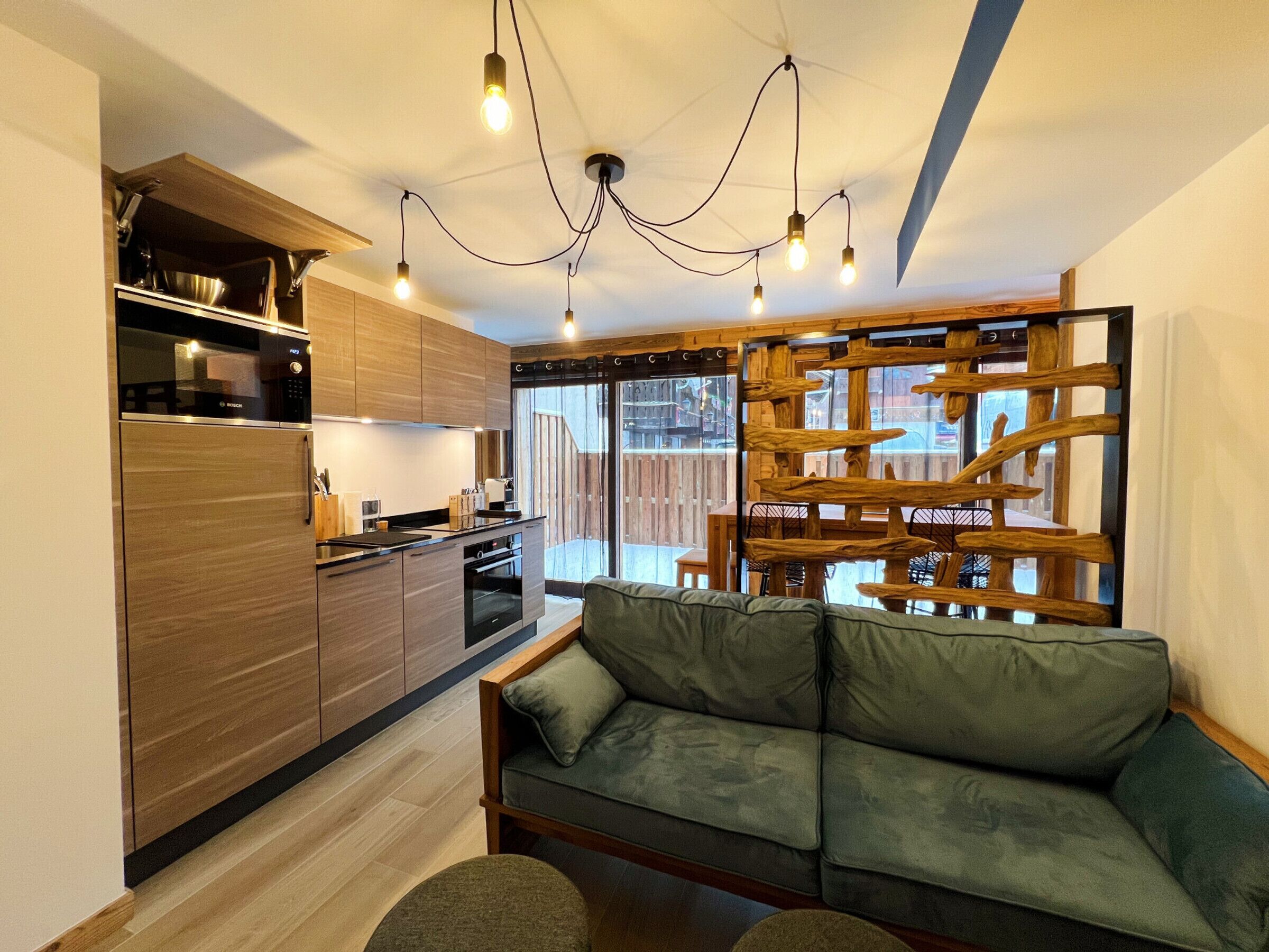 A modern kitchen with wooden cabinets, a built-in oven, and a dining area with a wooden partition.