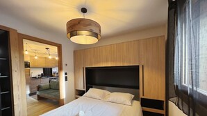 A modern bedroom with a large bed, wooden headboard, and a ceiling light fixture. - Charming apartment in Les Gets, 2 bedrooms, Wi-Fi, parking included (Les Gets)