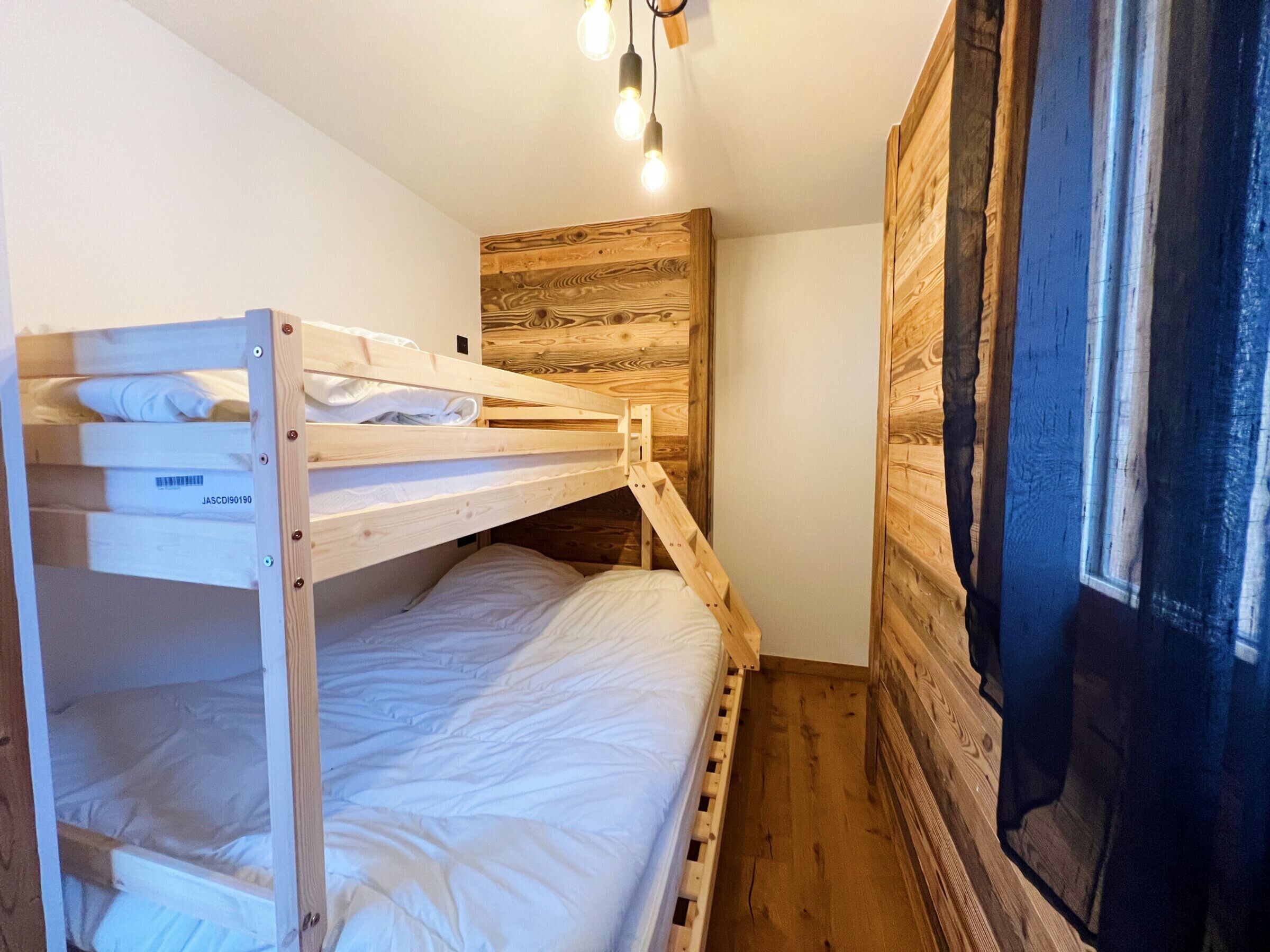 A bunk bed room with wooden walls and a window.