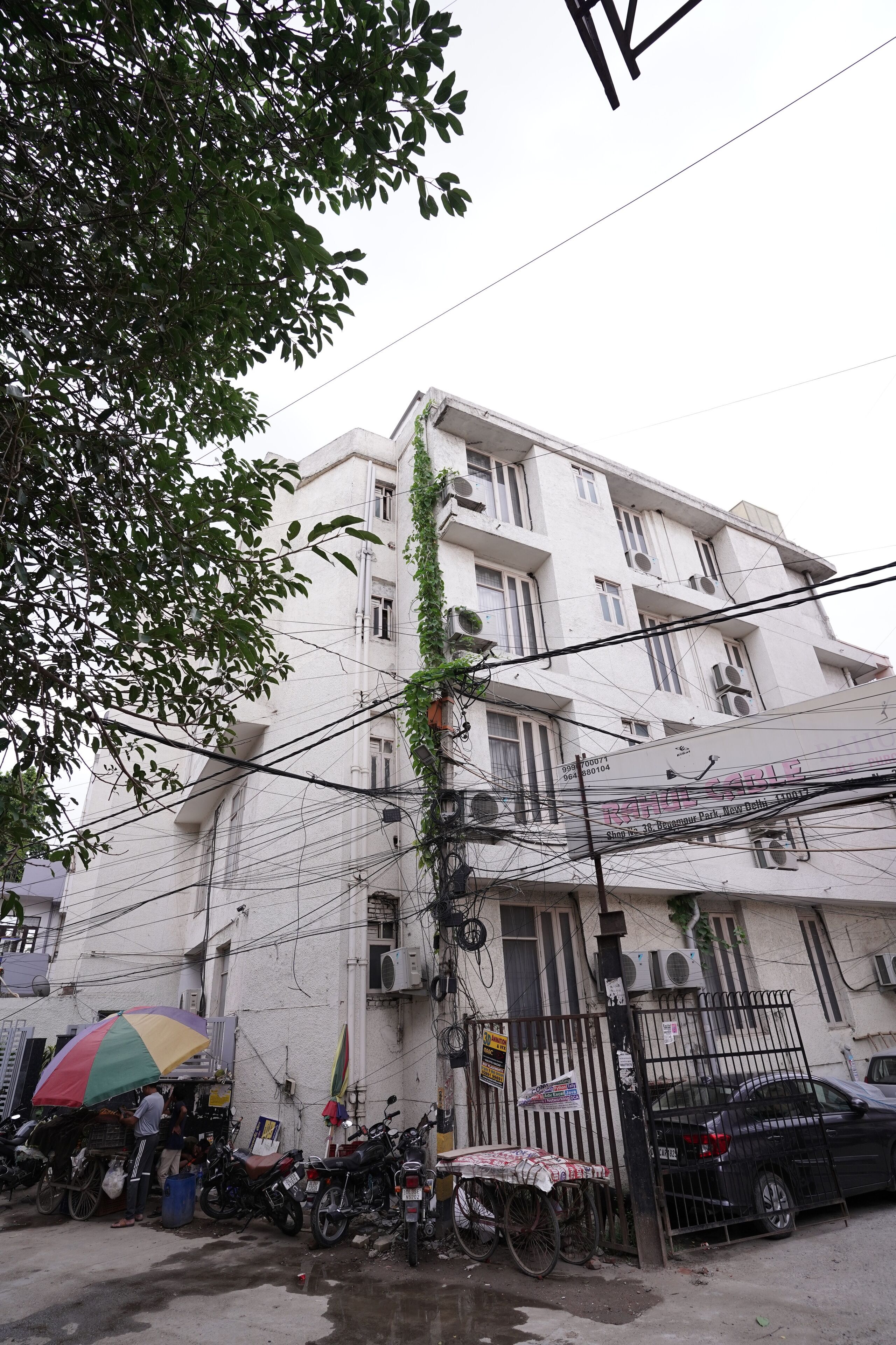 A multi-story building with balconies, air conditioning units, and a gated entrance.