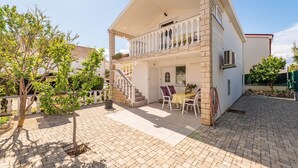 A two-story house with a balcony, a patio with outdoor furniture, and a garden area. - 2 bedroom lovely apartment in Vir (Vir)