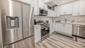 A modern kitchen with stainless steel appliances, white cabinetry, and a herringbone-patterned backsplash. - Cozy and Tastefully Furnished 1BR Guest Suite Close to Spruce Meadows SW Calgary (Calgary)