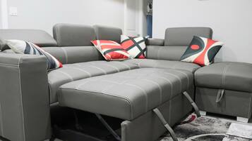 En grå modulsofa med sovefunktion, fremhævet af tre puder med mønster.