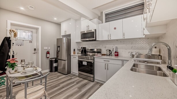 A modern kitchen with white cabinetry, stainless steel appliances, and a marble countertop. - Cozy and Tastefully Furnished 1BR Guest Suite Close to Spruce Meadows SW Calgary (Calgary)