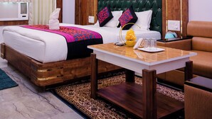 Una habitación de hotel moderna con un cabecero capitonado, un ventilador de techo, una cama con una manta de colores, una mesita de noche y un sillón de cuero marrón.