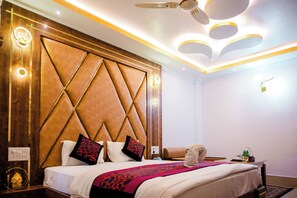 A hotel room with a large bed, a wooden headboard, and a ceiling fan.