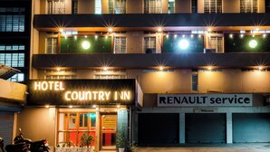 Un edificio de varios pisos con un letrero que indica Hotel Country Inn y un servicio Renault.