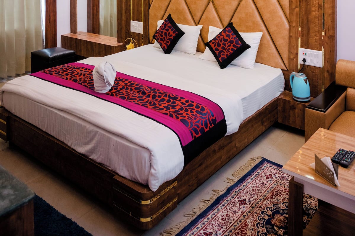 A hotel room with a large bed, wooden headboard, bedside tables, and a ceiling fan.